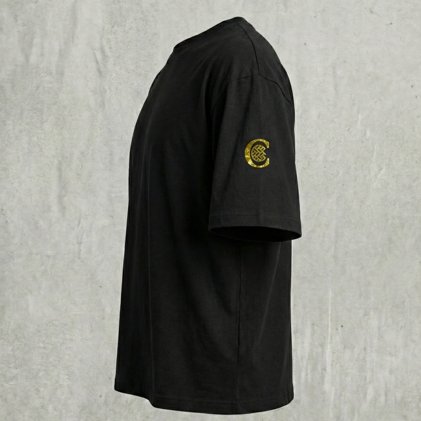 Side view of black tee showing gold C sleeve emblem.