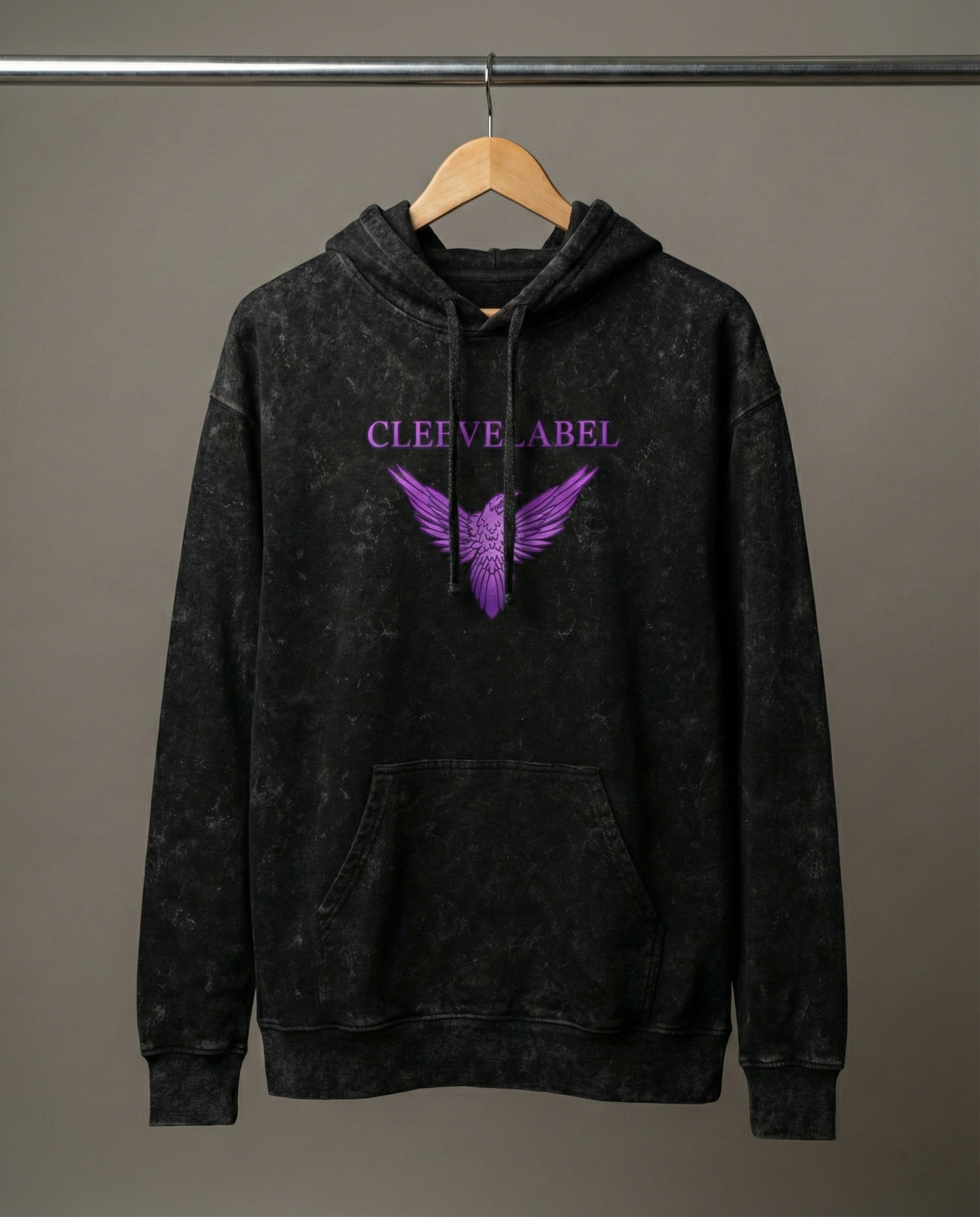 Black acid-wash Cleevelabel Salvation hoodie hanging on wooden hanger, front view with purple wing graphic and washed texture.