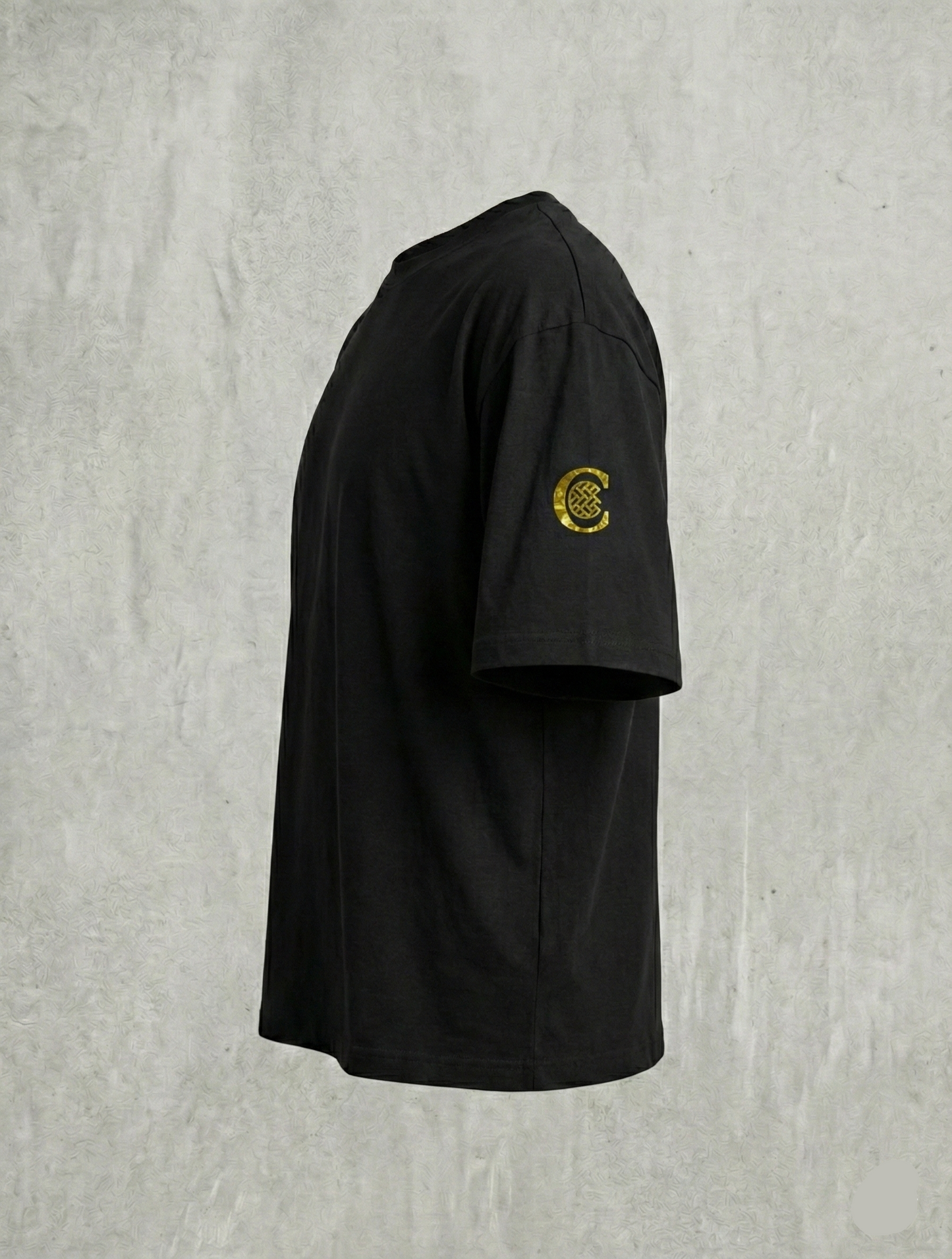 Side view of black tee showing gold C sleeve emblem.