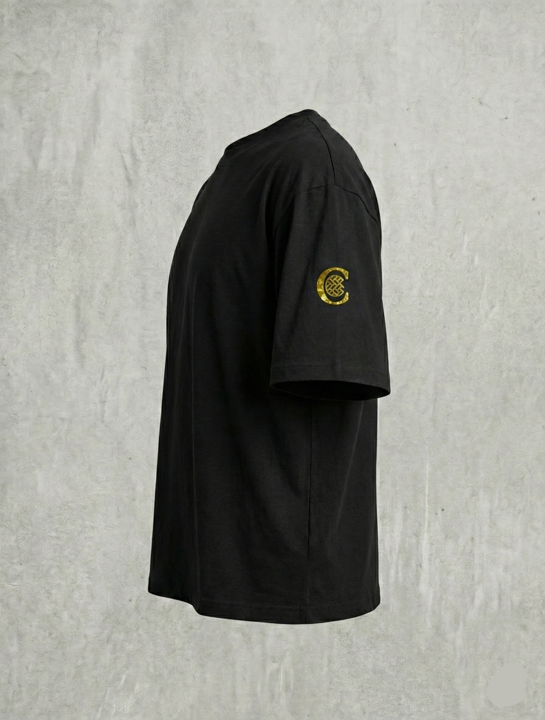 Side view of black tee showing gold C sleeve emblem.