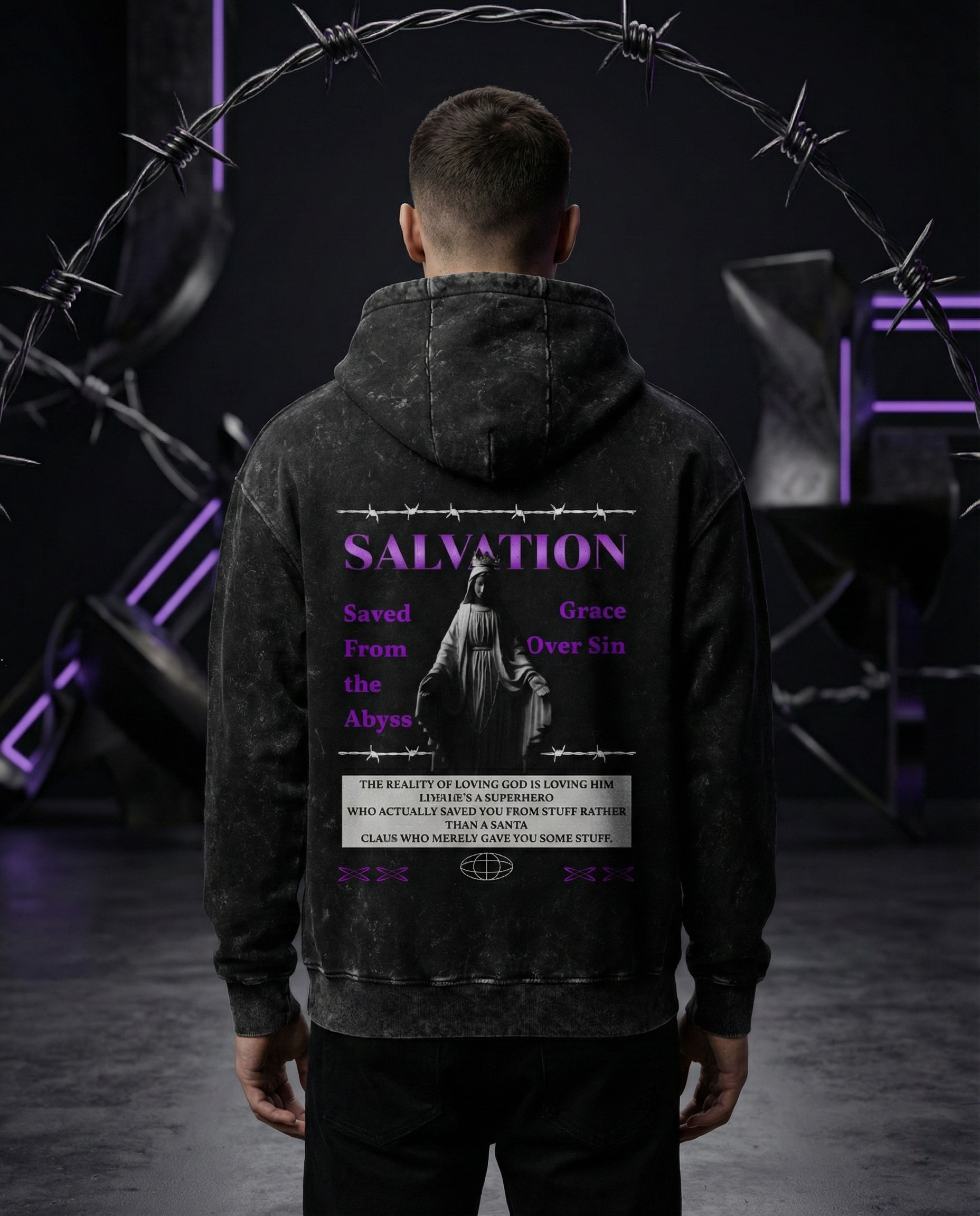 Male model wearing black acid-wash Salvation hoodie, back view with purple statue graphic and barbed wire design in futuristic dark studio.