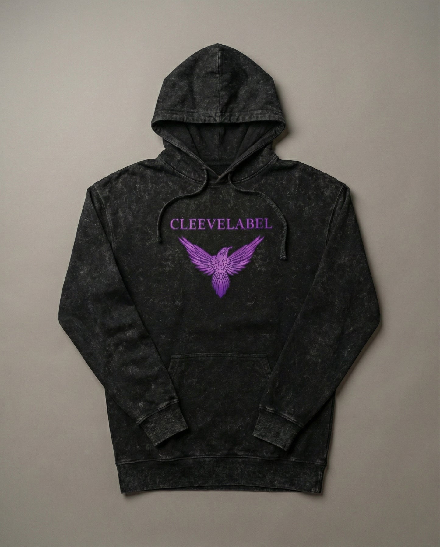 Black acid-wash hoodie laid flat on neutral background with Cleevelabel logo and purple wing graphic on front.