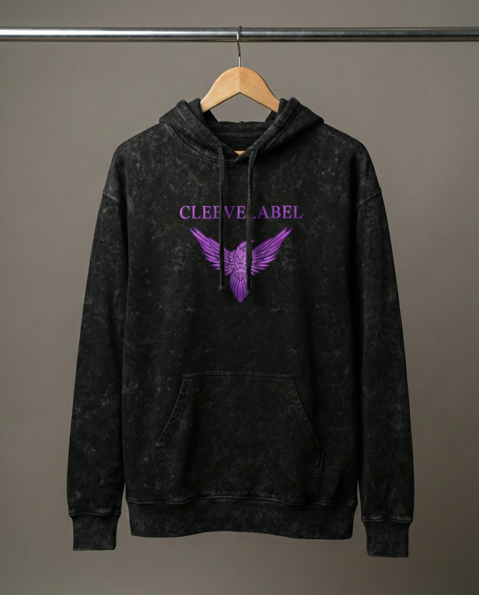 Black acid-wash Cleevelabel Salvation hoodie hanging on wooden hanger, front view with purple wing graphic and washed texture.